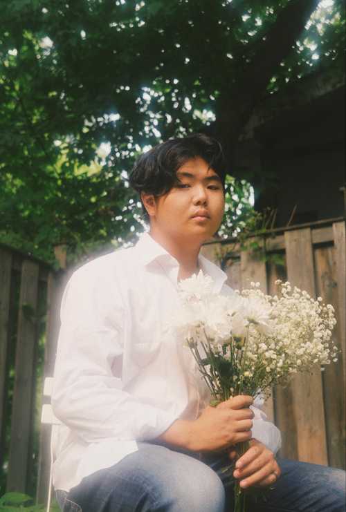 Picture of a male model posing with white flowers.